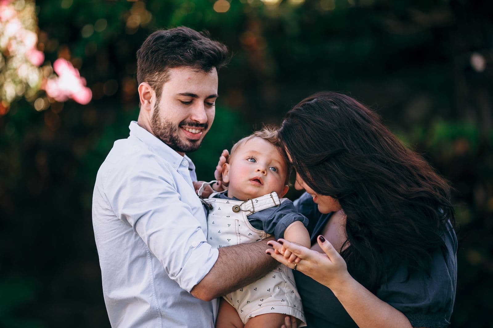 A young couple smiling with their baby in the garden